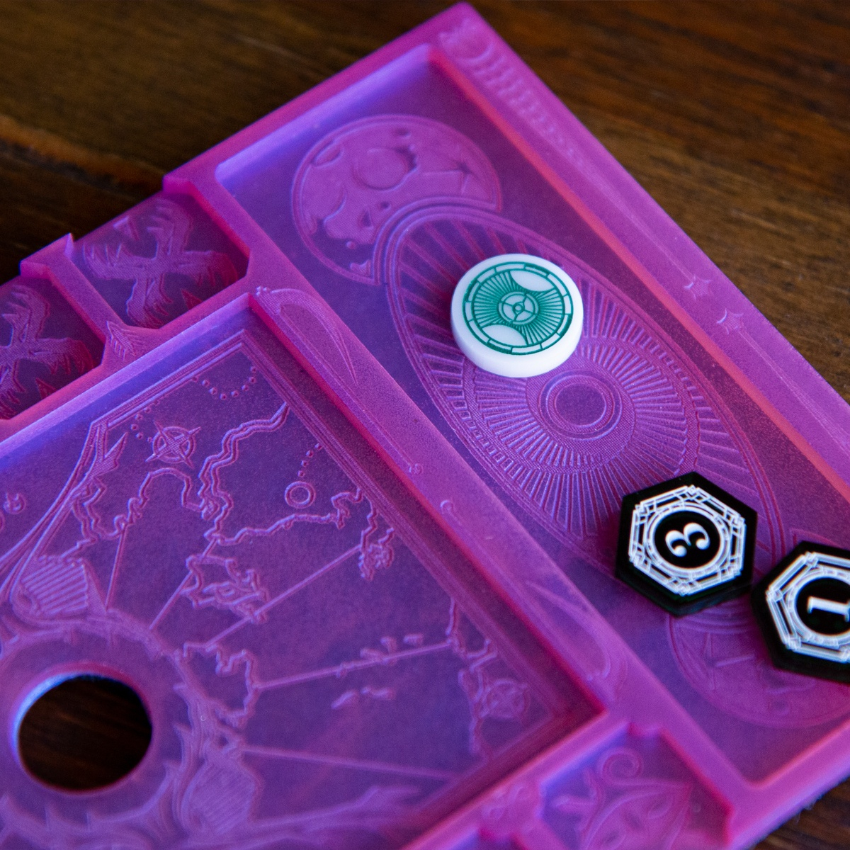 Close up of the Clue/Resource holder of the Dream Mythos Board, highlighting the moon and endless stairs designs from Lovecraft’s Dreamlands, a single Clue Token and two Resource Tokens, one on it’s three-value side and one on it’s one-value side sit in the holder section