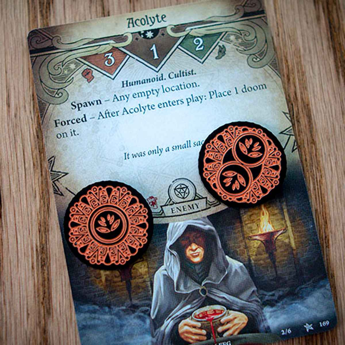 The one-value side and the two-value side of the Forgotten Limited Edition Doom Token represented by two different tokens on top of the Arkham Horror LCG card, Acolyte