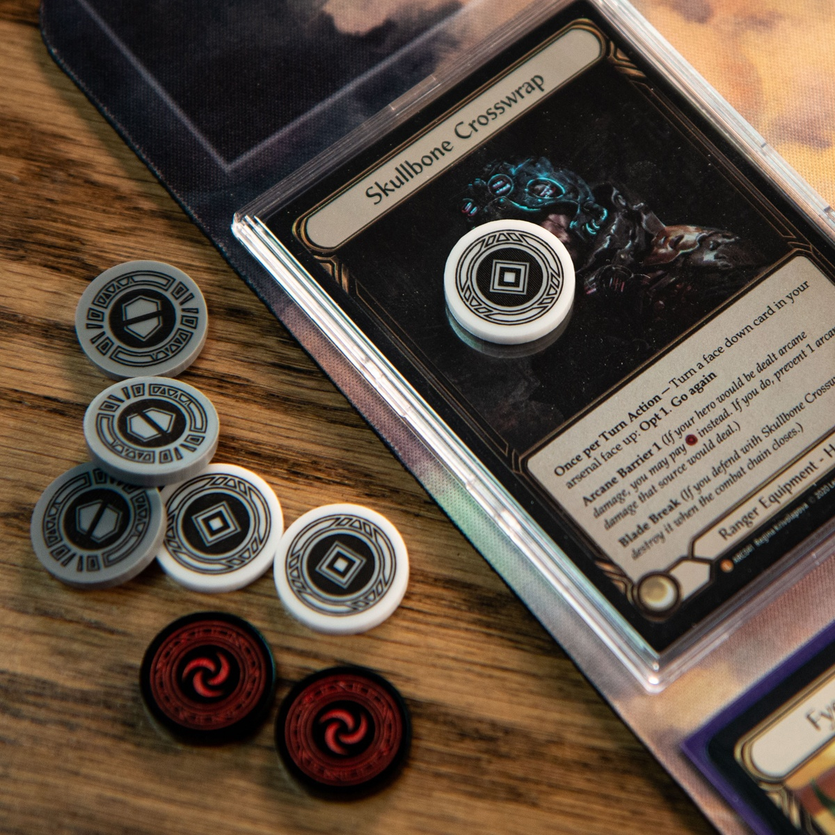 One Activation Token on top of the Flesh and Blood TCG card, Skullbone Crosswrap, to the left, Armor Tokens, additional Activation Tokens, and Resource Tokens wait to be used