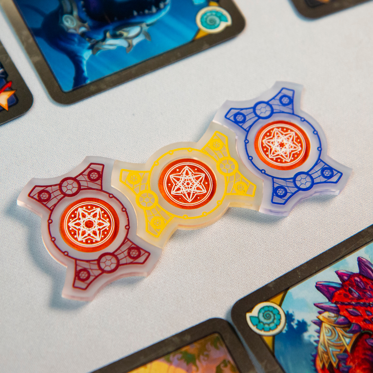 Red, yellow, and blue Bitter Winds Keys holding standard amber tokens in their center, surrounded by Keyforge cards