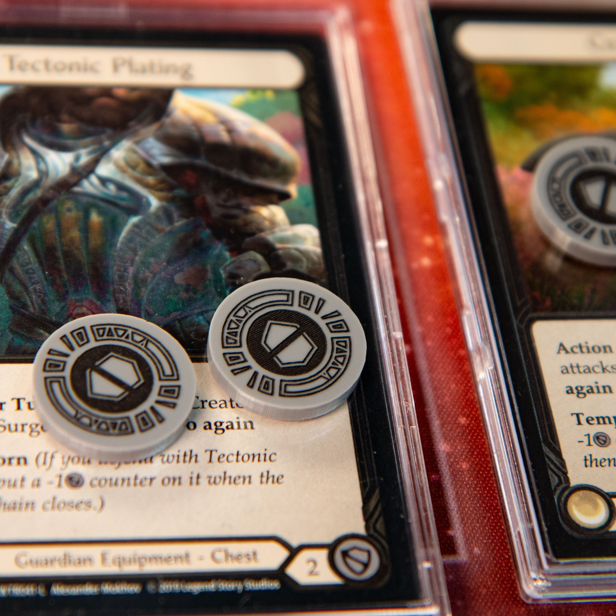 Two Armor Tokens being used to denote the Battleworn status on the Flesh and Blood TCG card, Tectonic Plating