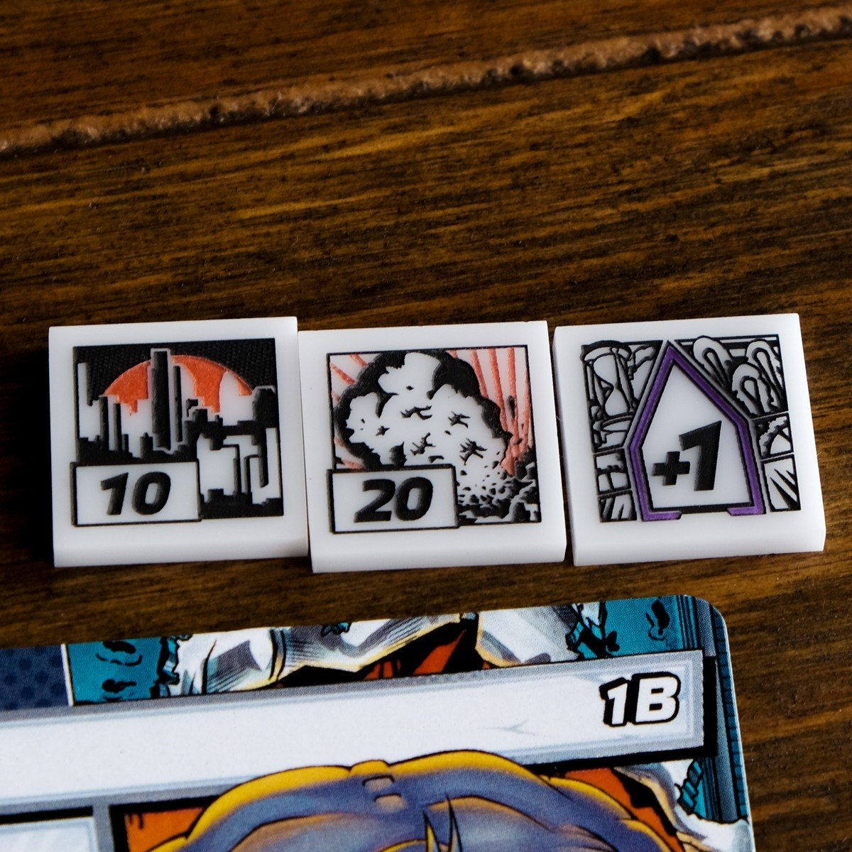 Close up of the 10 Threat, threatened city, token, it's flip side, the 20 Threat, giant explosion, token as well as one Acceleration token, all above a scheme card from Marvel Champions LCG