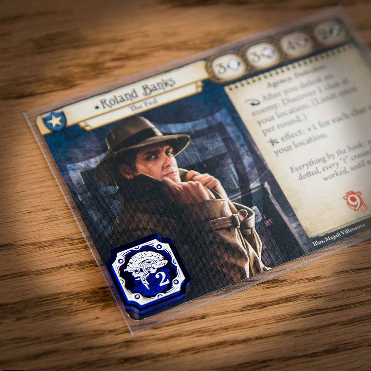 A two-value Sanity Token on top of the Arkham Horror LCG investigator, Roland Banks