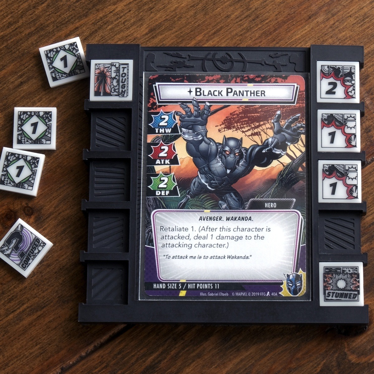 All designs from the full set of Hero Cosmic Tokens are displayed in and around a Cosmic Board featuring the card Black Panther from Marvel Champions LCG